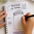 Une femme utilisant un tracker d'épargne sur un ordinateur portable, entourée d'un carnet et d'un café.
